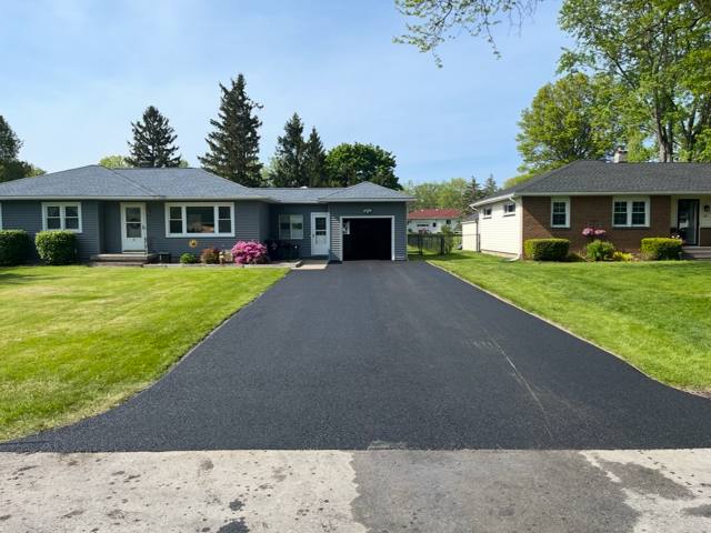New asphalt driveway at a gray ranch home