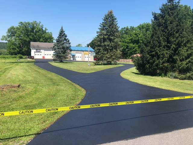 Glossy sealcoated Y-shaped driveway leading to commercial garages