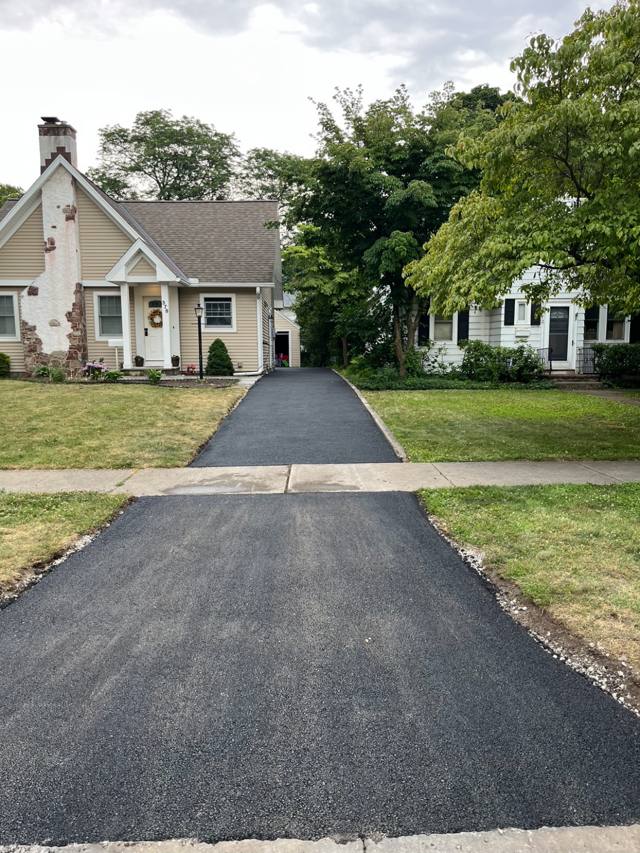Long narrow paved driveway beside a cottage-style home
