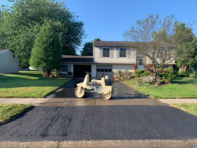 Roller on a freshly paved driveway at a split-level home