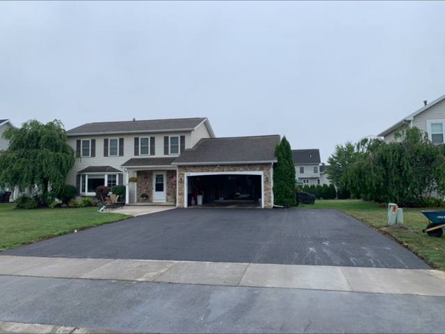 Sealcoated wide driveway at a two-story home with stone garage