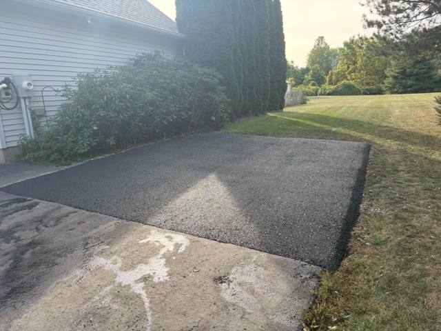 New asphalt pad extending a driveway beside a house