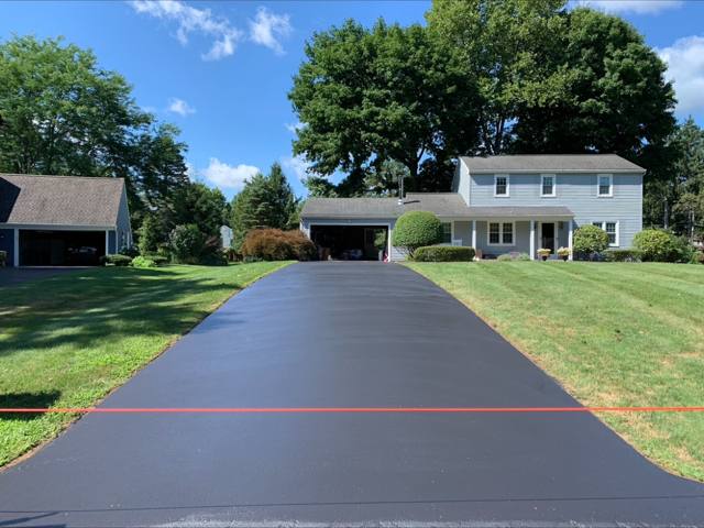 Freshly sealcoated sweeping driveway at a two-story home