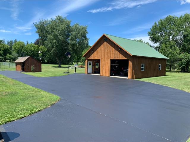 Sealcoated driveway in front of a wooden barn garage