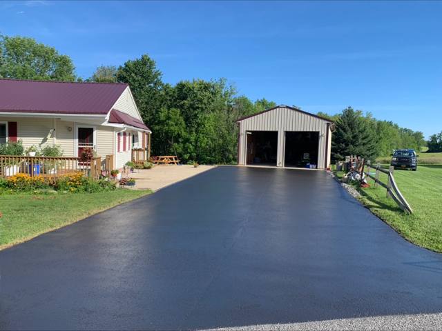 Long sealcoated driveway leading to a pole barn