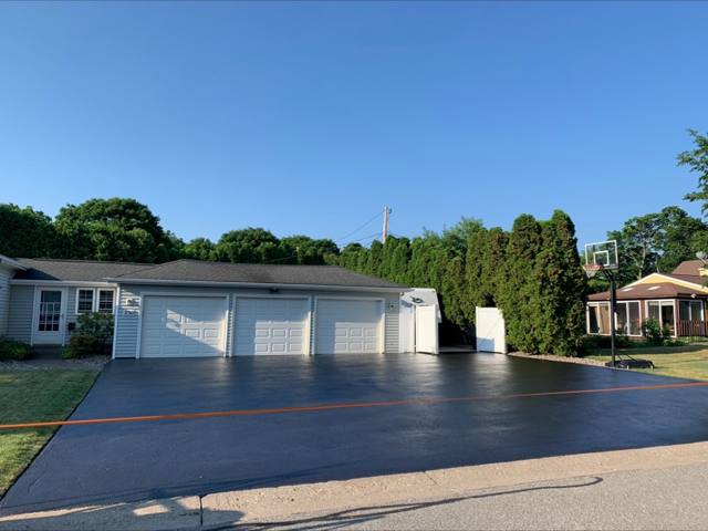 Wide glossy sealcoated driveway in front of a three-car garage