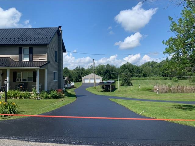 Sealcoated driveway winding past a farmhouse to a garage