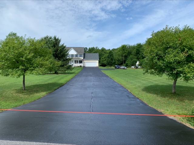 Long straight sealcoated driveway lined with trees