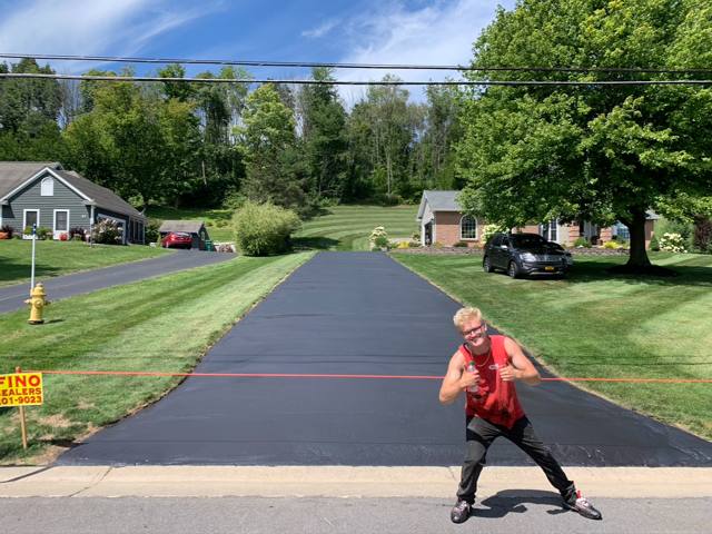 Crew member celebrating a freshly sealcoated driveway